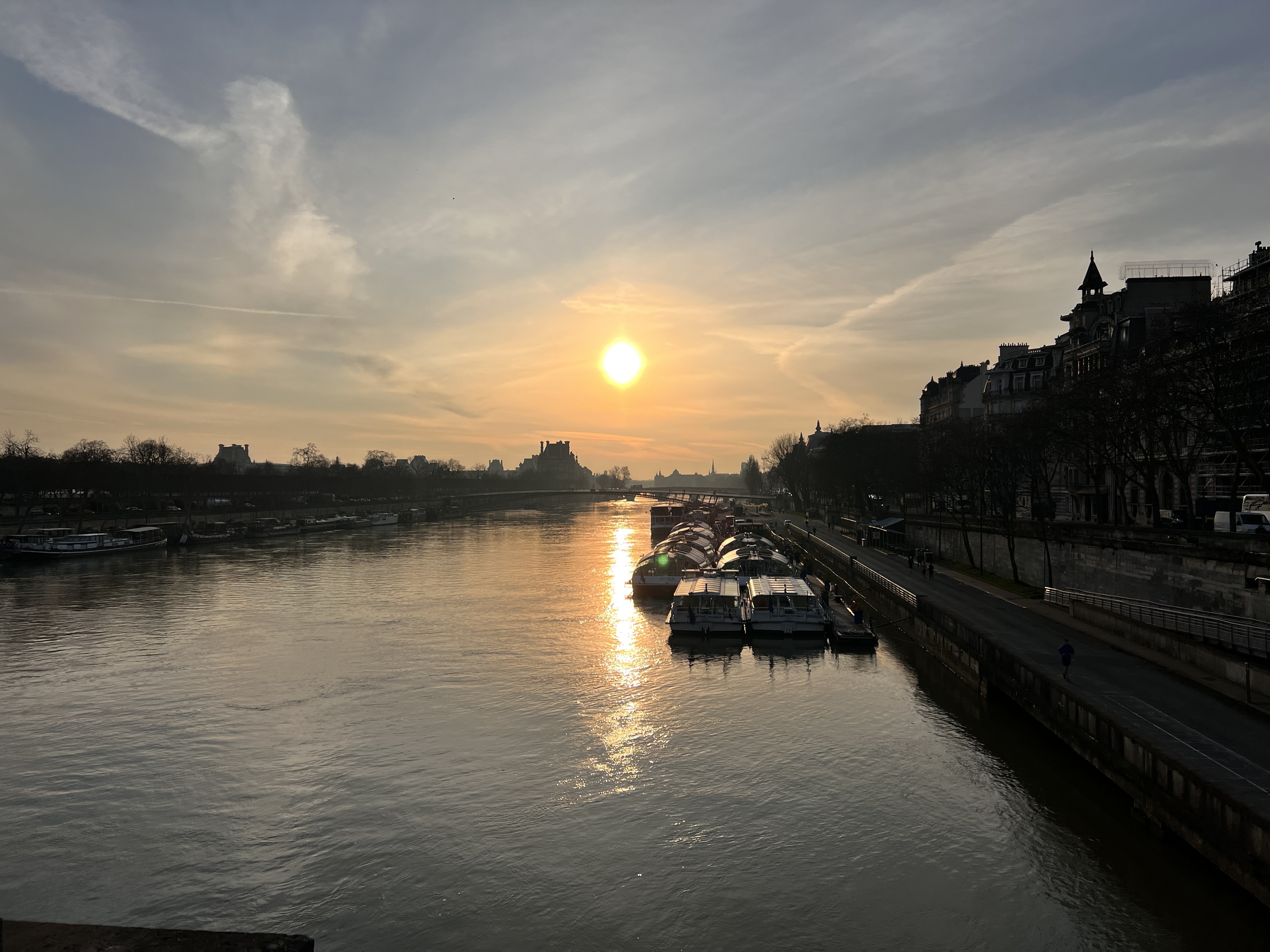 Paris Seine river at dawn seen from a bridge. The river, the Louvre palace, sunrise over the river. 