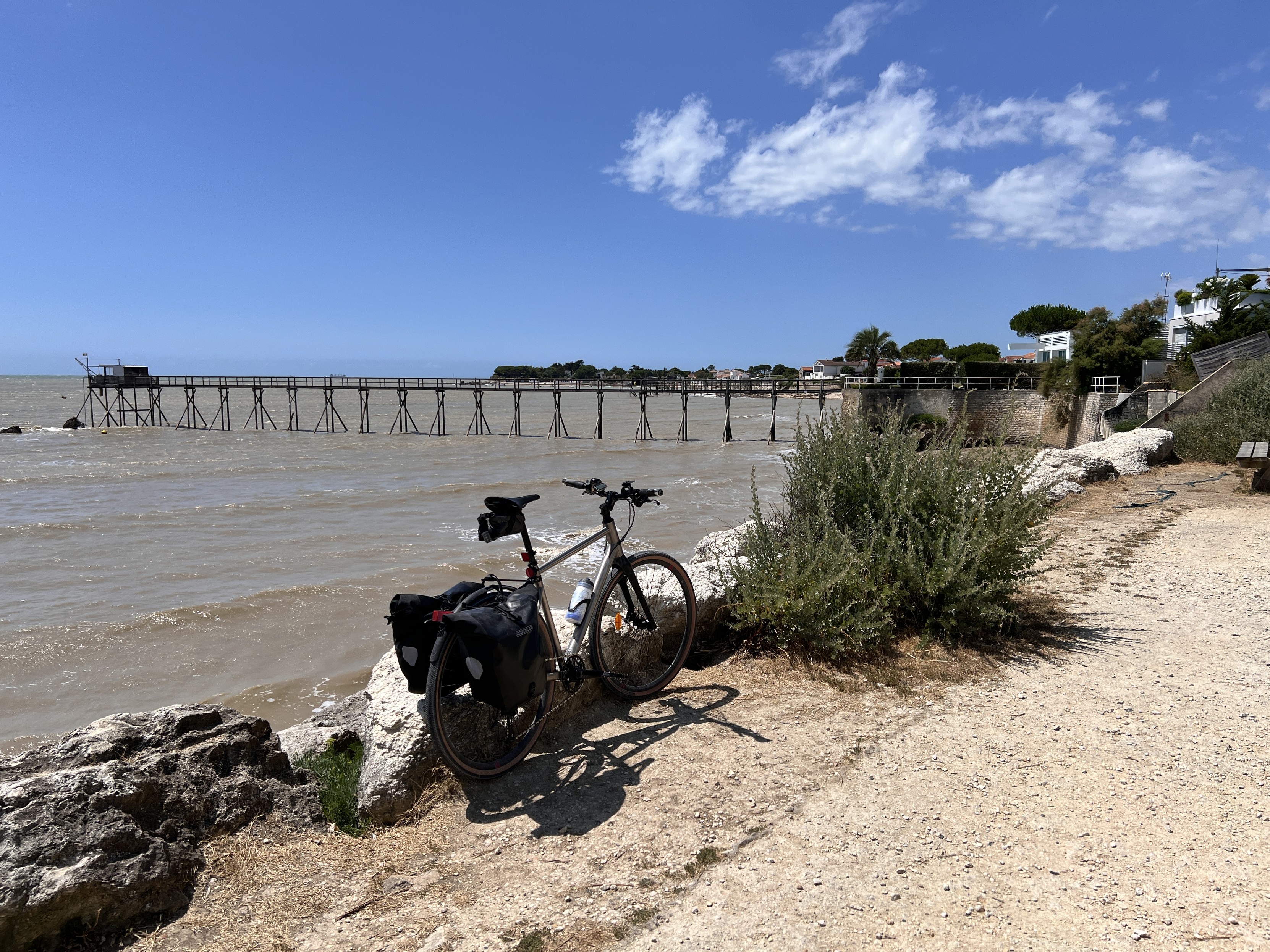 Mon vélo appuyé sur un rocher, devant la mer assez agitée . Au loin un carrelet, petite cabane sur pilots pour pêcher au filet.