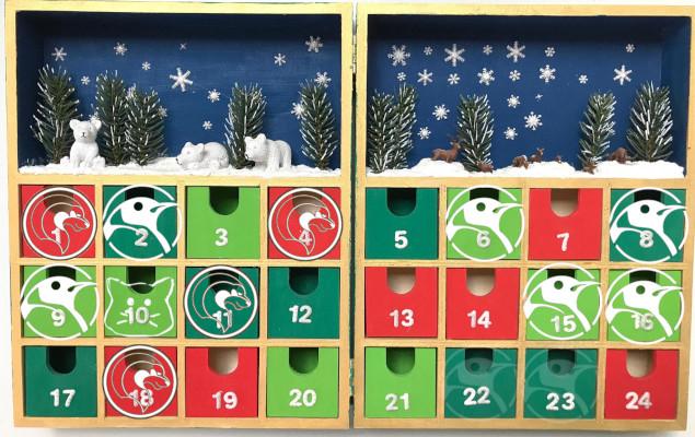 Un calendrier de l'avent en bois à tiroirs. Une silhouette blanche est ajoutée sur les tiroirs correspondant à des jours d'événement libriste : logo de l'ALDIL, tête de chaton ou tête de manchot.
Les logos sur le 22 et le 23 décembre sont atténués.